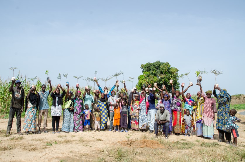 Community members posing for a picture, holding seedlings